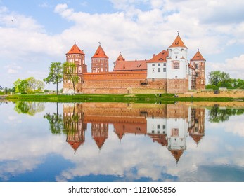 Mir, Belarus. Castle Complex Mir reflected in lake On Sunny Day with blue sky Background. Old medieval Towers and walls of traditional fort from unesco world heritage list