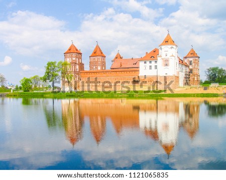 Mir, Belarus. Castle Complex Mir reflected in lake On Sunny Day with blue sky Background. Old medieval Towers and walls of traditional fort from unesco world heritage list