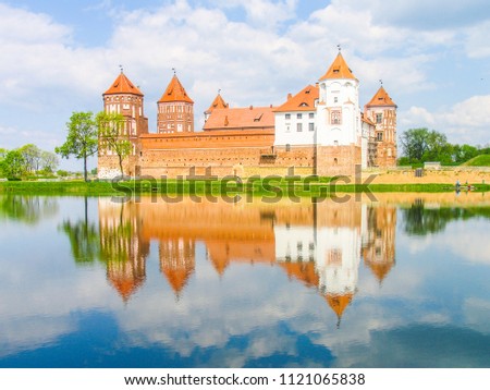 Mir, Belarus. Castle Complex Mir reflected in lake On Sunny Day with blue sky Background. Old medieval Towers and walls of traditional fort from unesco world heritage list
