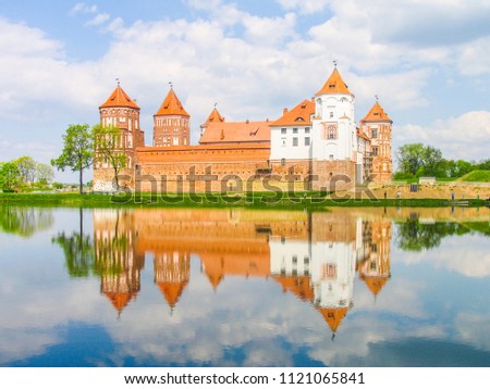 Mir, Belarus. Castle Complex Mir reflected in lake On Sunny Day with blue sky Background. Old medieval Towers and walls of traditional fort from unesco world heritage list