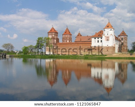 Mir, Belarus. Castle Complex Mir reflected in lake On Sunny Day with blue sky Background. Old medieval Towers and walls of traditional fort from unesco world heritage list
