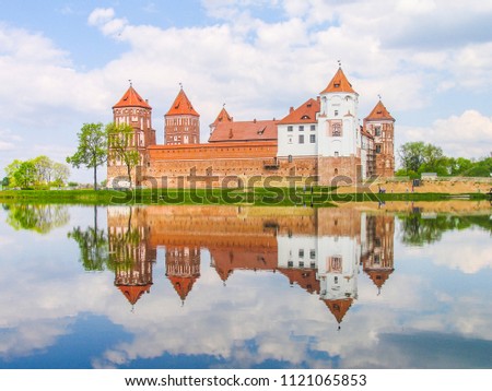 Mir, Belarus. Castle Complex Mir reflected in lake On Sunny Day with blue sky Background. Old medieval Towers and walls of traditional fort from unesco world heritage list