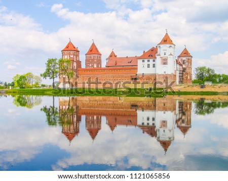 Mir, Belarus. Castle Complex Mir reflected in lake On Sunny Day with blue sky Background. Old medieval Towers and walls of traditional fort from unesco world heritage list