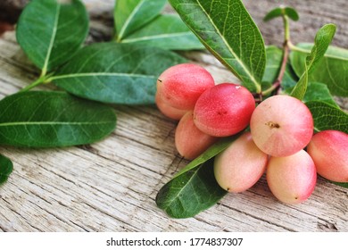 Miracle fruit and leaves on wood background