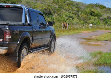 Ceará Mirim, Rio Grande Do Norte, Brazil - October 25 2015: A Black Car Moving Forward On A Flooded Dirt Road, Splashing The Water Around.