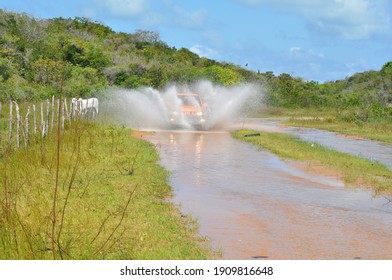 Ceará Mirim, Rio Grande Do Norte, Brazil - October 25 2015: A Car Moving Forward On A Flooded Dirt Road, Splashing The Water Around.