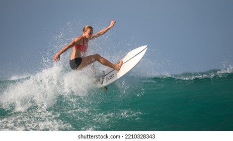 Mirissa, Sri Lanka - 04 09 2022: Athletic Female Surfer Completes The Aerial Maneuver On The Clear Big Wave. Keeping The Body Balance All The Way. High-skilled Professional Surfer Woman In Action.