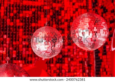 Mirror disco balls suspended in a club among shiny red mosaic in the shape of squares, disco texture beautiful background