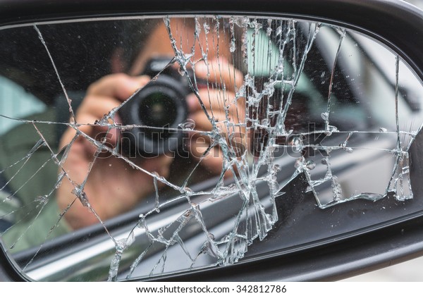 Mirror\
image of a photographer in the broken car\
mirror