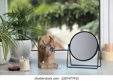 Mirror, Jewelry, Candles And Houseplants On Light Grey Stone Window Sill