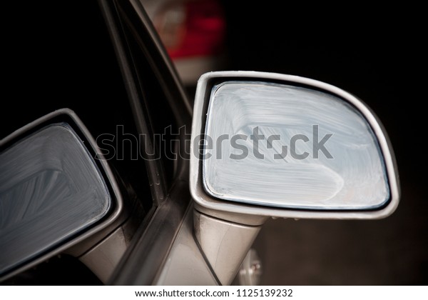 Mirror next to car\
painted with white paint