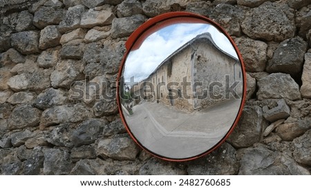 Mirror on stone wall. Reflection in rural area.