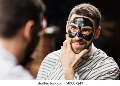 Mirror reflection of handsome man with peel-off mask on face