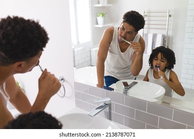 Mirror Reflection Of Hispanic Father And Son Brushing Teeth Together In Bathroom. Unaltered, Family, Togetherness, Hygiene And Routine Concept.