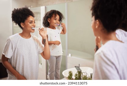 Mirror reflection of mom and girl brushing teeth together while bonding, having fun and enjoy quality time. Child development, learning or dental care for oral hygiene girl cleaning teeth in bathroom - Powered by Shutterstock