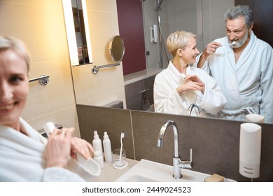 Mirror reflection of woman looking at man brushing teeth in bathroom - Powered by Shutterstock