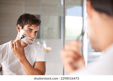 Mirror, shaving and face of man in bathroom for facial grooming, wellness and skincare at home. Health, skincare and serious male person shave beard for hygiene, cleaning and hair removal with razor