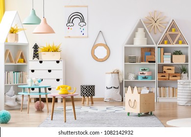 Mirror in wooden frame hanging on the wall in white room interior for kids with books and toys