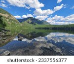 Mirrored reflection on lake with partly cloudy sunny skies