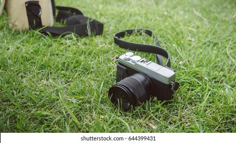 Mirrorless camera, lens and mini backpack on glass nature background