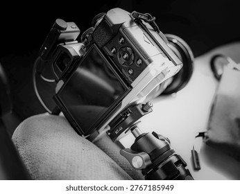 Mirrorless camera mounted on compact tripod inside vehicle, rear screen and controls visible in monochrome automotive photography setup
