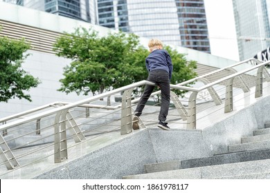 Mischievous Boy Slides Down The Railing On A City Walk