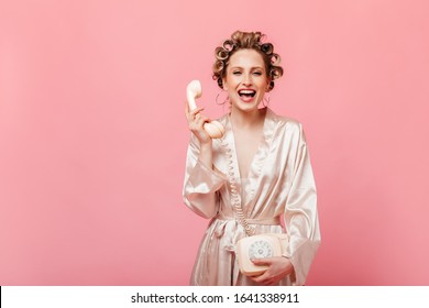 Mischievous girl in silk robe is laughing. Housewife with hair curlers talking on phone. - Powered by Shutterstock