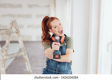 Mischievous Woman Shooting The Camera Aiming A Handheld Power Drill During Home Renovations