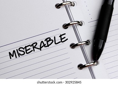 MISERABLE word written on notebook