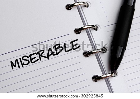 MISERABLE word written on notebook