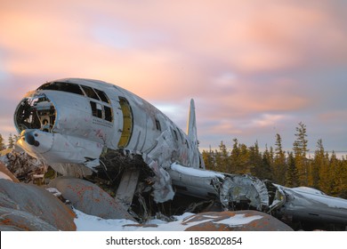 Miss Piggy Plane Wreck In Churchill, Manitoba With Pink, Cloudy Sunset Background In Frame With Snow On Rocks In Front Of Crash Landing Site. 