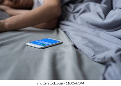 Missed Call Phone From Someone Via Mobile Smart Phone While Asian Man Sleeping On Bed In Late Morning. Miss An Appointment Concept