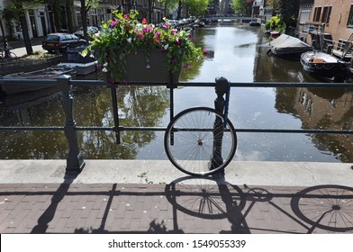 A Missing Bicycle Locked On A Bridge Over A Canal In Netherlands. 
Only One Of The Tires And The Shadow Of The Bike Are Left To Remind Of The Stolen Vehicle. 
A Beautiful Water Reflection Behind It.