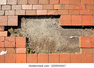 Missing Bricks in Sidewalk with Dirt and Plastic Spoon