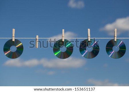 A missing CD in the row on a clothesline, attached with clothespins.