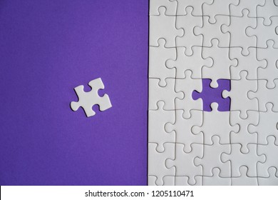 Missing jigsaw puzzle pieces. Business concept. Fragment of a folded white jigsaw puzzle and a pile of uncombed puzzle elements against the background of a Violet surface.