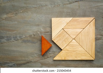 a missing piece in a square built from tangram pieces, a traditional Chinese puzzle game, slate rock background