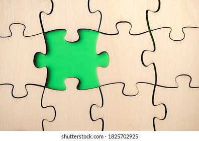 Missing puzzle piece. Almost finished, large jigsaw puzzle made of wood on green background. Concept for moving forward, understand a complicated process or filled in gaps of knowledge