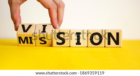 Mission vision symbol. Businessman hand turns wooden cubes and changes the word 'mission' to 'vision'. Beautiful yellow table, white background, copy space. Business and mission vision concept.