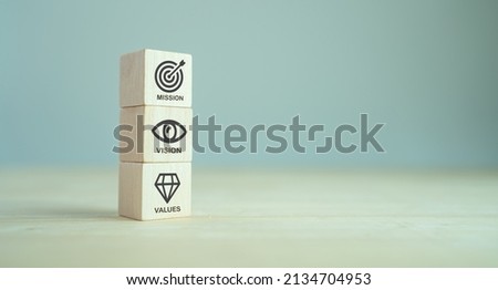 Mission, vision and values of company. Purpose business concept. The wooden cube with mission, vision and values symbols on grey background, copy space. Modern stacking design. Business presentation. 