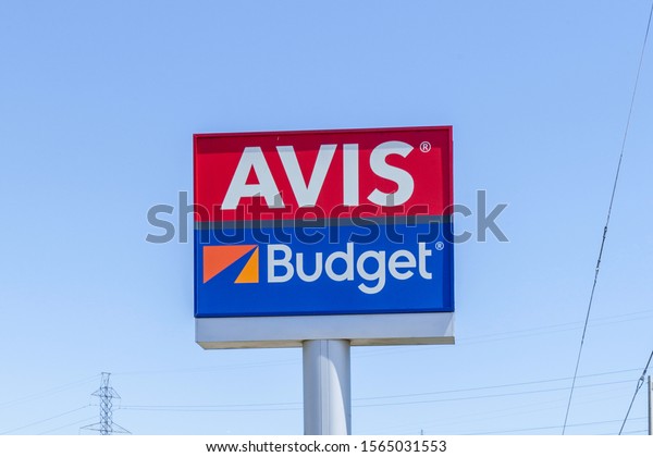 Mississauga, Ontario, Canada - May 13, 2018: Sign of\
Avis Budget with blue sky in background. Avis Budget Group, Inc. is\
the American parent company of Avis Car Rental, Budget Car Rental.\
