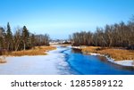 Mississippi River flows north toward Bemidji Minnesota near hiway 2 on a sunny day. This winter scene with snow and ice is a few miles from the source at Lake Itasca