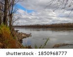 The Missouri River on a clear sunny fall day with colorful autumn leaves and brush under blue skies with big puffy clouds in Augusta, MO