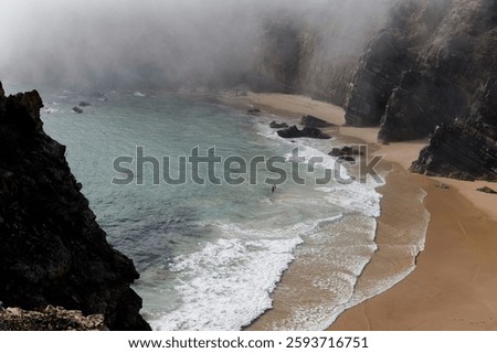 Mist drapes over the rugged cliffs of Praia do Tonel as gentle waves kiss the secluded shore.