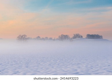 Mist on the ground over a snow-covered hillside landscape on the Mangfall valley in Upper Bavaria at dusk, Germany - Powered by Shutterstock