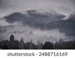 A mist shrouded Mount Owen that dominates the western skyline of the mining and tourist town of Queenstown, Tasmania, Australia