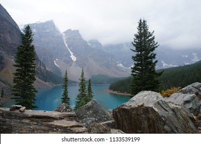 Mist Swirls Around The Mountains That Ring The Turquoise Waters Of Lake Moraine, Alberta, Canada