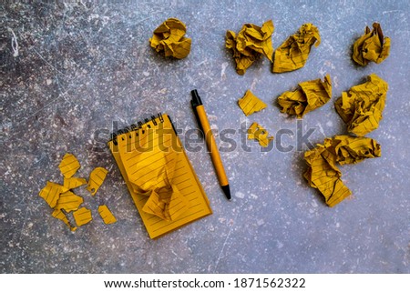 Mistake, frustration, trying to to find a solution to the problem concept. Workspaces with crumpled ball paper and torn pages around the kraft notebook. Learning from errors and failures.