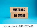 Mistakes to avoid message written on wooden blocks with blue background. Conceptual mistakes to avoid symbol. Copy space.