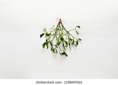 Mistletoe traditional Christmas bunch on white wooden background, flat lay, space for a greeting text